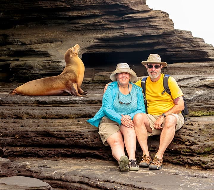 Galapagos Cruise Guests sitting on a rock next to Sea Lion