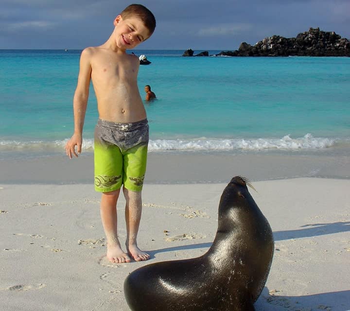 Kid and pup posing at a white sand beach in Galapagos