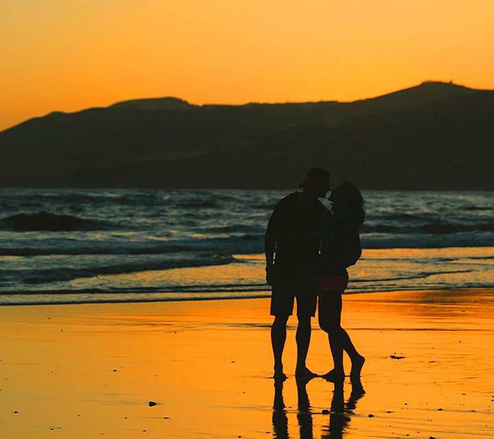 Silhouette of honeymooners walking on the beach at sunset in the Galpagos Islands