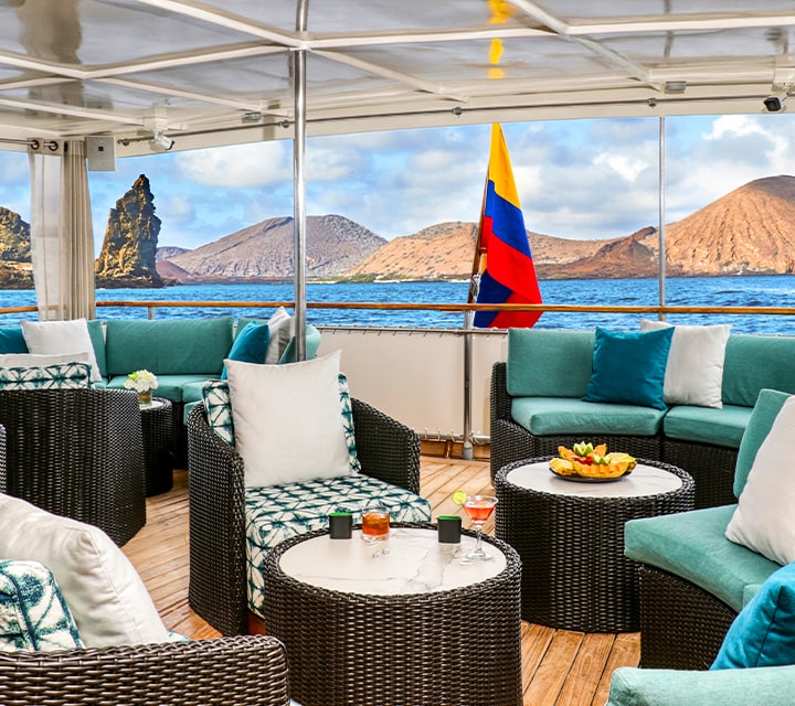 Covered outdoor deck on Grace Yacht with Kicker Rock in Bartolome Island, Galapagos in the background