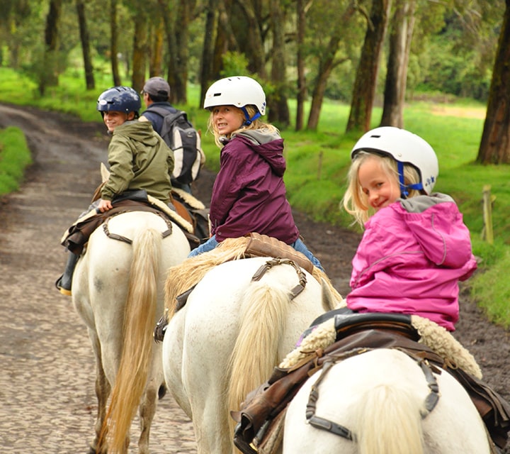 Kids wearing helmets on a guided horseback ride through a national park in Patagonia