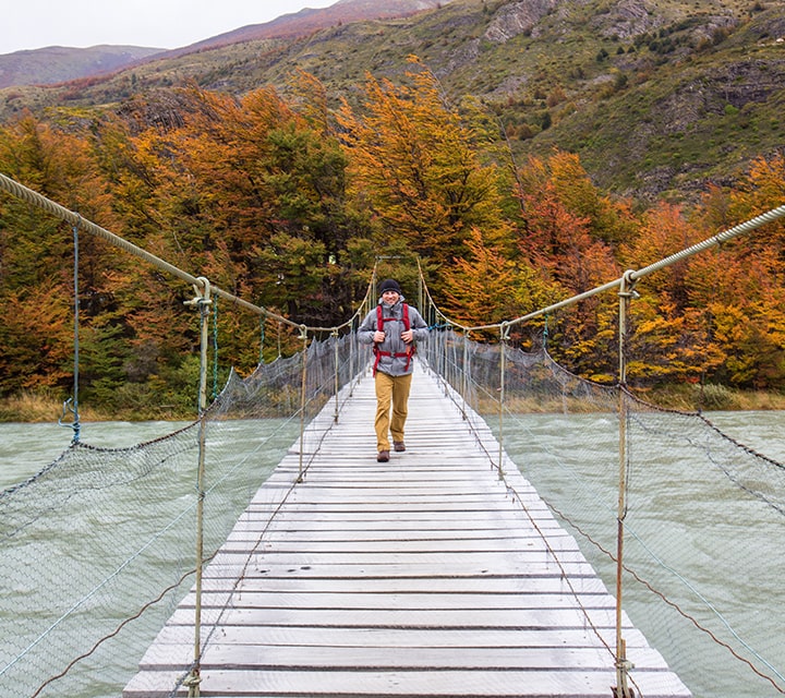 Solo traveler crossing a Patagonian bridge on a day trip to a national park