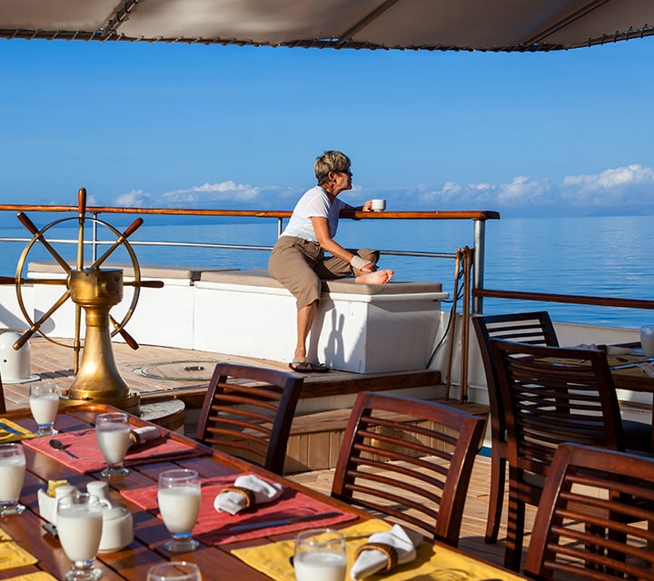 A woman with a cup of coffee waiting for breakfast to be served aboard Grace Yacht, Galapagos Islands