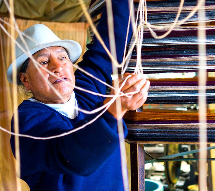An indigenous Ecuadorian woman weaving fabric into merchandise, a pass down tradition of their ancestors