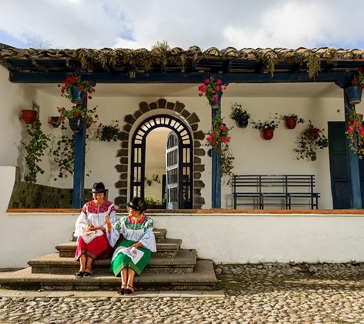 Ecudorian women sitting infront of the colonial-era working farm turned boutique hotel, Hacienda Zuleta in Ecuador