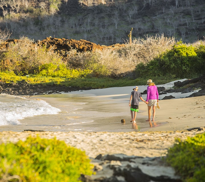 A mother and son walking hand-in-hand on a Galapagos beach