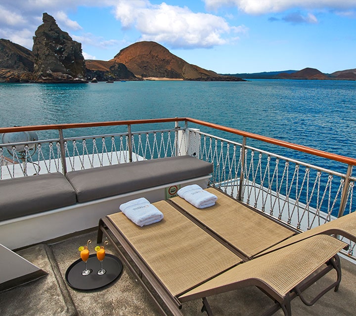Grace Yacht deck lounge with cocktails next to Bartolome Island, Galapagos