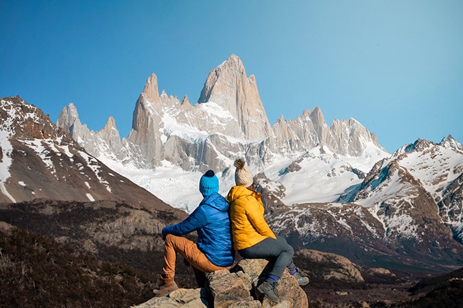 A couple sitting on rocks looking out to Mt. Fitz Roy in Patagonia
