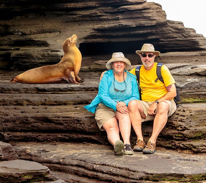 couple in galapagos posing with a sea lion
